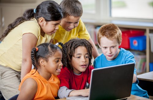 Fünf Kinder, die gemeinsam auf einen Laptop schauen.