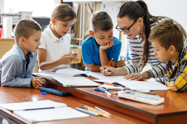 Eine Lehrerin und vier Kinder schreiben gemeinsam