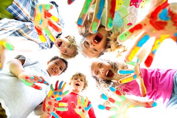 Kinder zeigen ihre Hände, die mit bunten Farben bemalt sind.